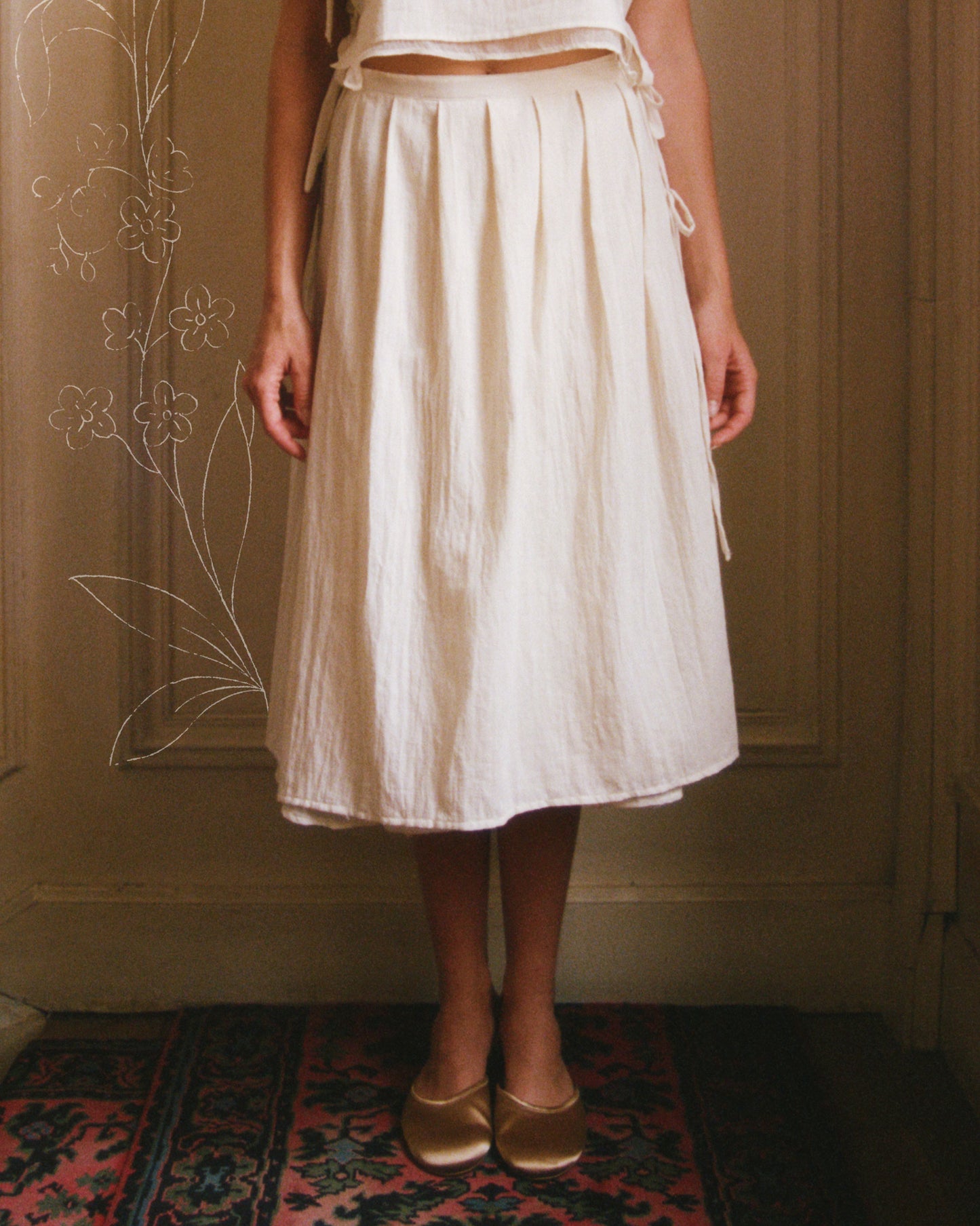 Model wearing The Pleated Skirt .01 in unbleached handwoven cotton, handcrafted in Paris, France, showing pleated front and wrap closure