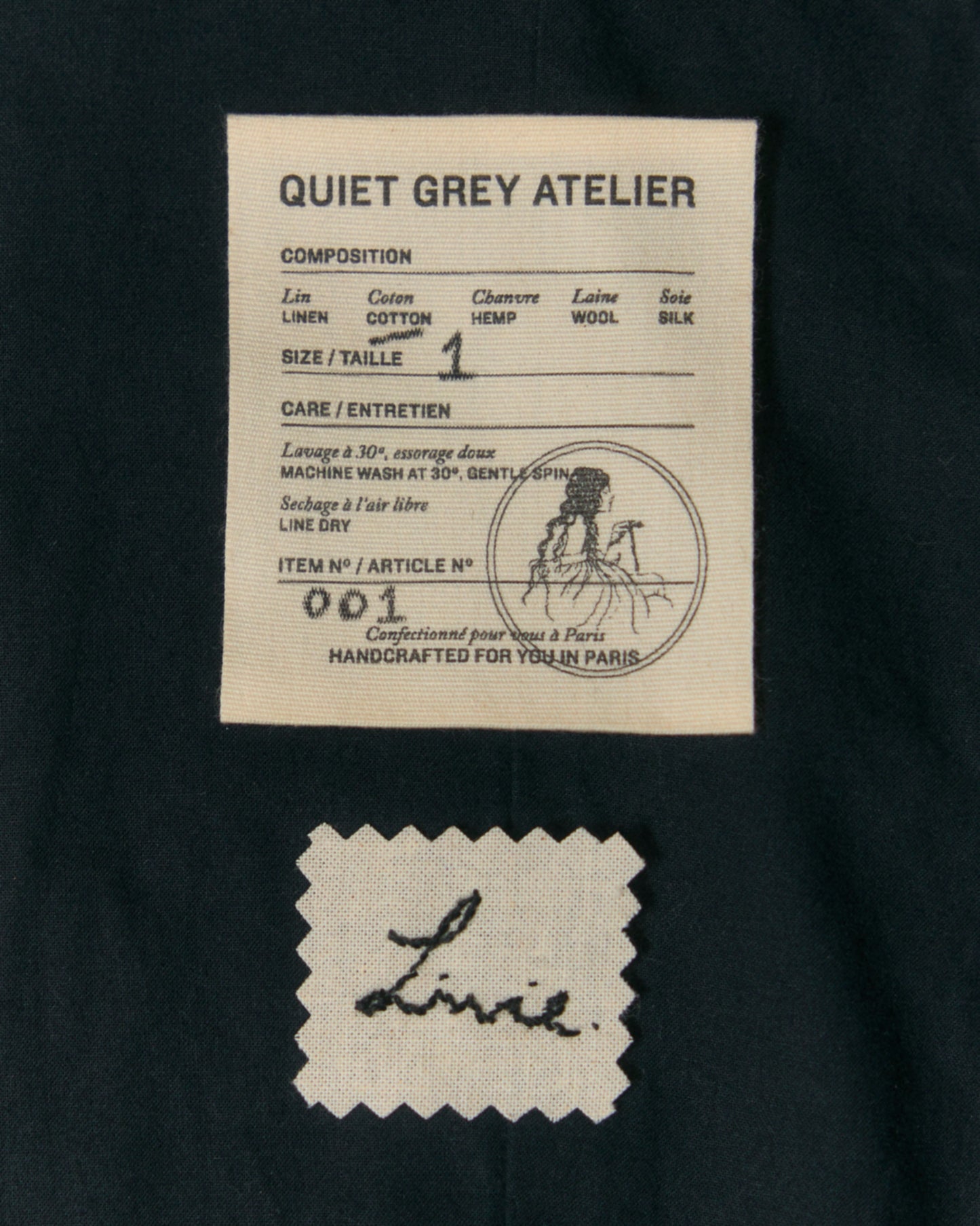 Detail of label and hand-embroidered name on the inside of black cotton summer dress.