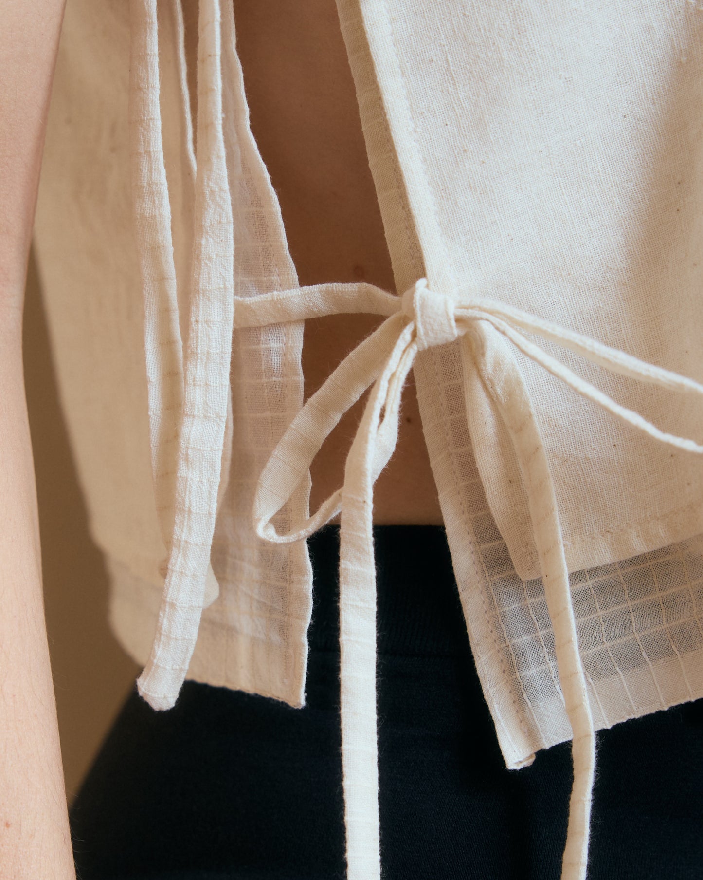 Detail of side ties on white summer top. Handcrafted in Paris.