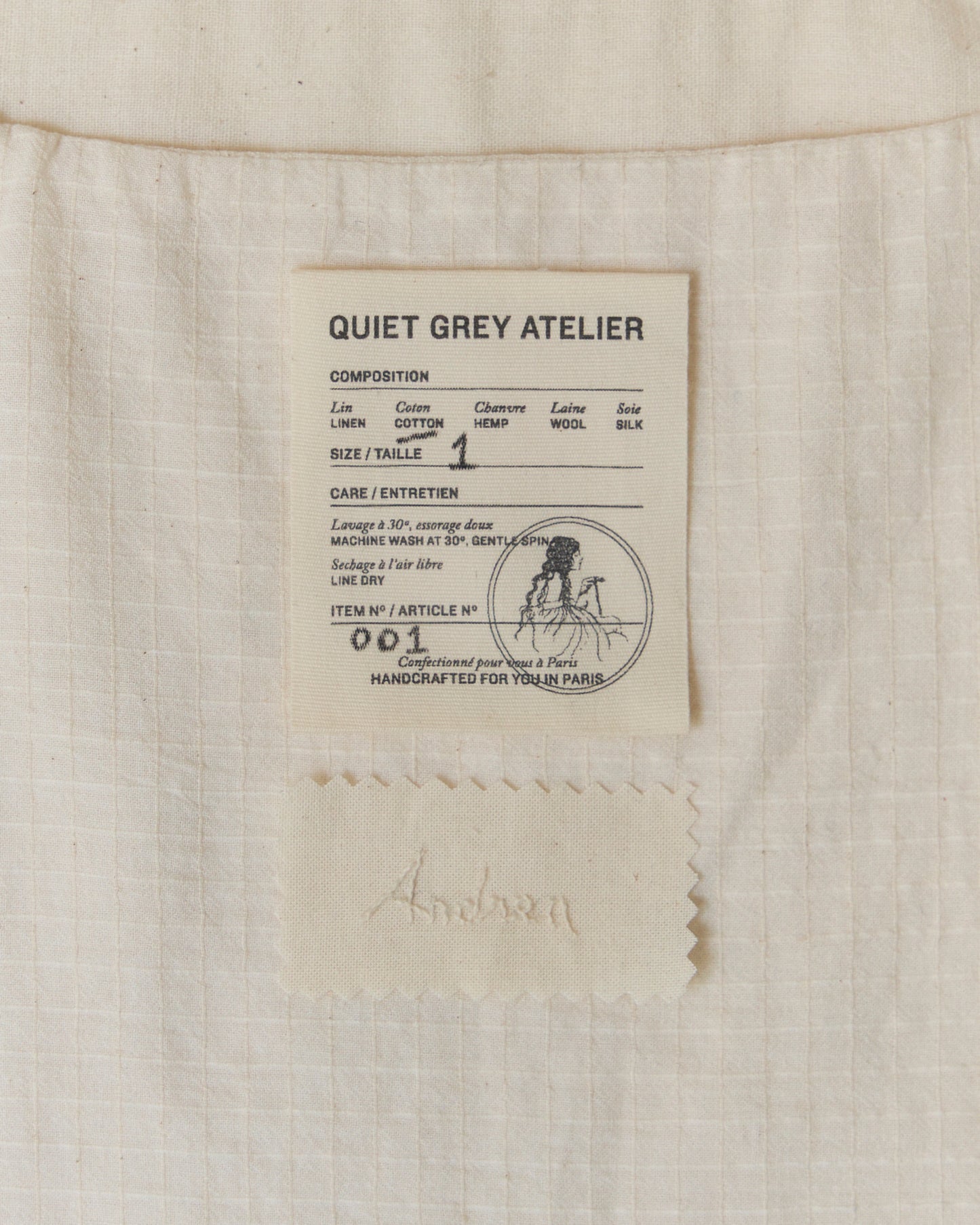 Detail of label and hand-embroidered name on the inside of white top.