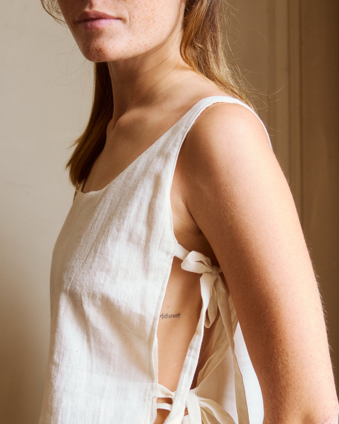 Close-up of adjustable side lacets on white cotton summer top. Made in Paris.
