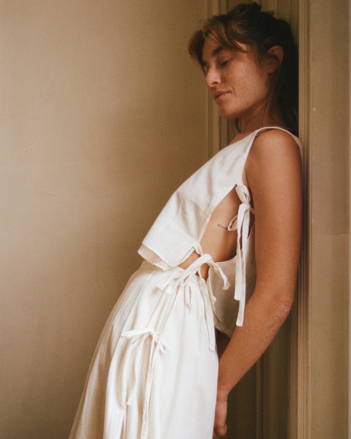 Model leaning agains wall, showing adjustable side lacets on handwoven cotton top.