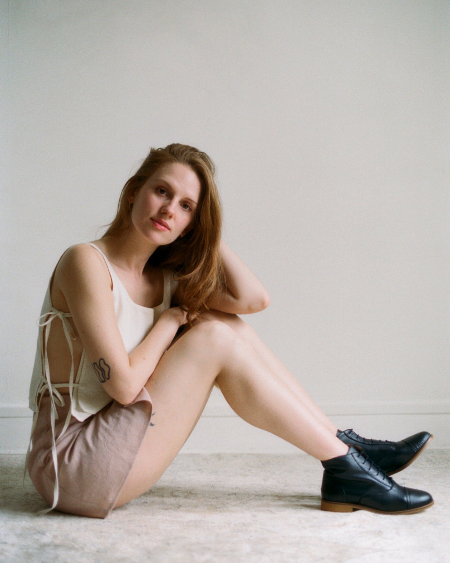 Model sitting on the floor wearing Mini Wrap Skirt .01 paired with Lacets Top .01 for complete summer outfit.