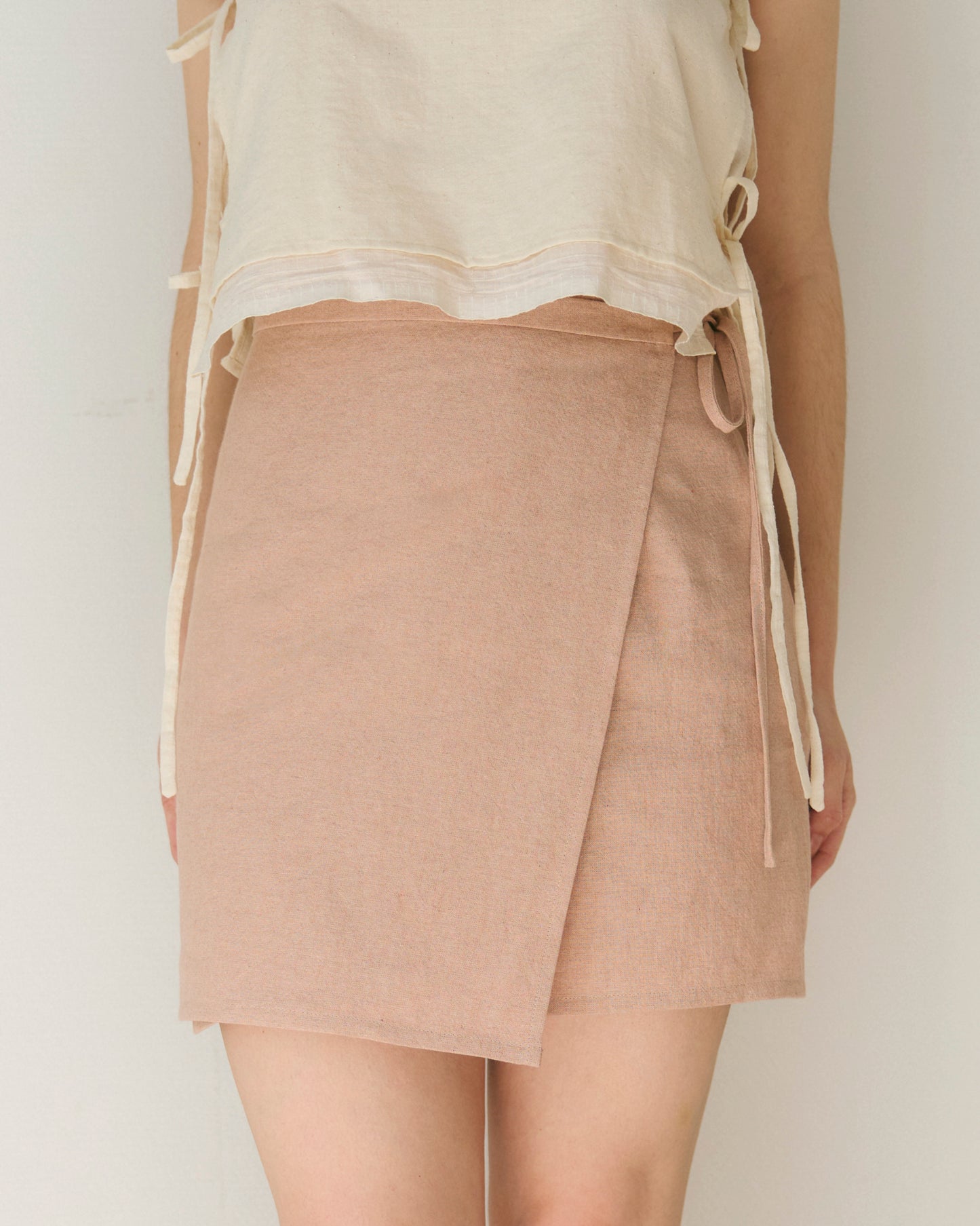 Front view of mini-skirt in pale pink, made from organic cotton and linen blend. Crafted in France.