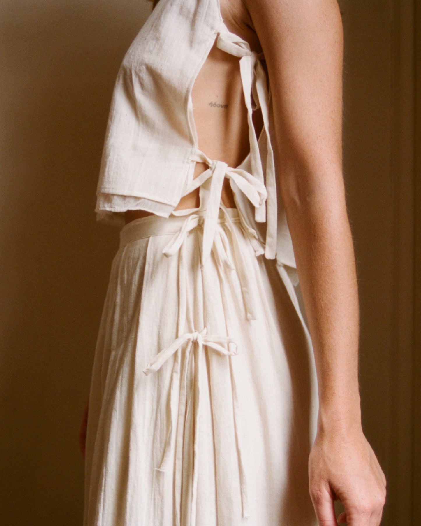 Side view showing the adjustable closure of The Pleated Top 01 and The Pleated Skirt 01. There are 4 lacets total, 2 on each piece.
