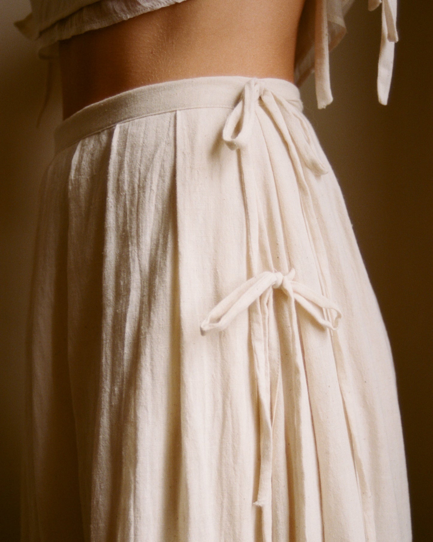 Side ties detail on Pleated Skirt .01 showing romantic touch and adjustable closure.